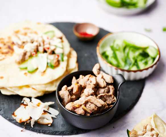 Solomillo de cerdo con salsa de coco picante, pan de ajo naan y ensalada de pepino Solomillo de cerdo con salsa de coco picante, pan de ajo naan y ensalada de pepino