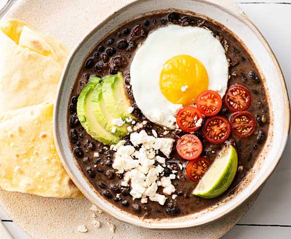 Stoofpot van zwarte bonen met spiegeleieren en maïstortilla's