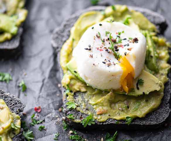 Fatias de pão escuro com sementes, abacate e ovo escalfado