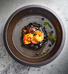 Tagliatelle al nero di seppia con pomodorini neri e gamberi