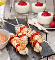 Brochetas de rape y langostinos con emulsión de escalivada. Vasitos de limón y fresas.