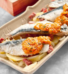 Filetes de sardina con patatas, jamón y salsa de tomate