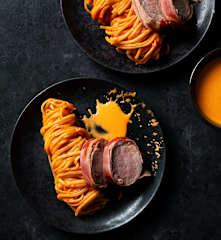 Lomo de cerdo con salsa de pimiento y nidos de pasta cremosa.