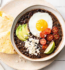 Stoofpot van zwarte bonen met spiegeleieren en maïstortilla's