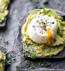 Fatias de pão escuro com sementes, abacate e ovo escalfado